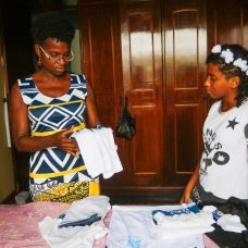 Tatiane e a filha, Swahili, separam camisas do uniforme da rede municipal