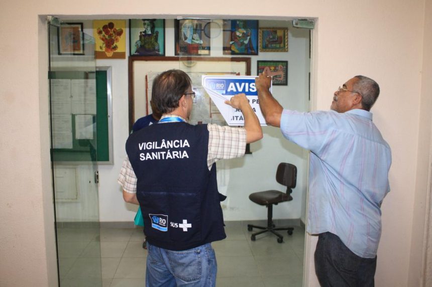 Fiscal da Vigilância Sanitária remove aviso de interdição na Unirio. Foto: Nelson Duarte / Prefeitura do Rio