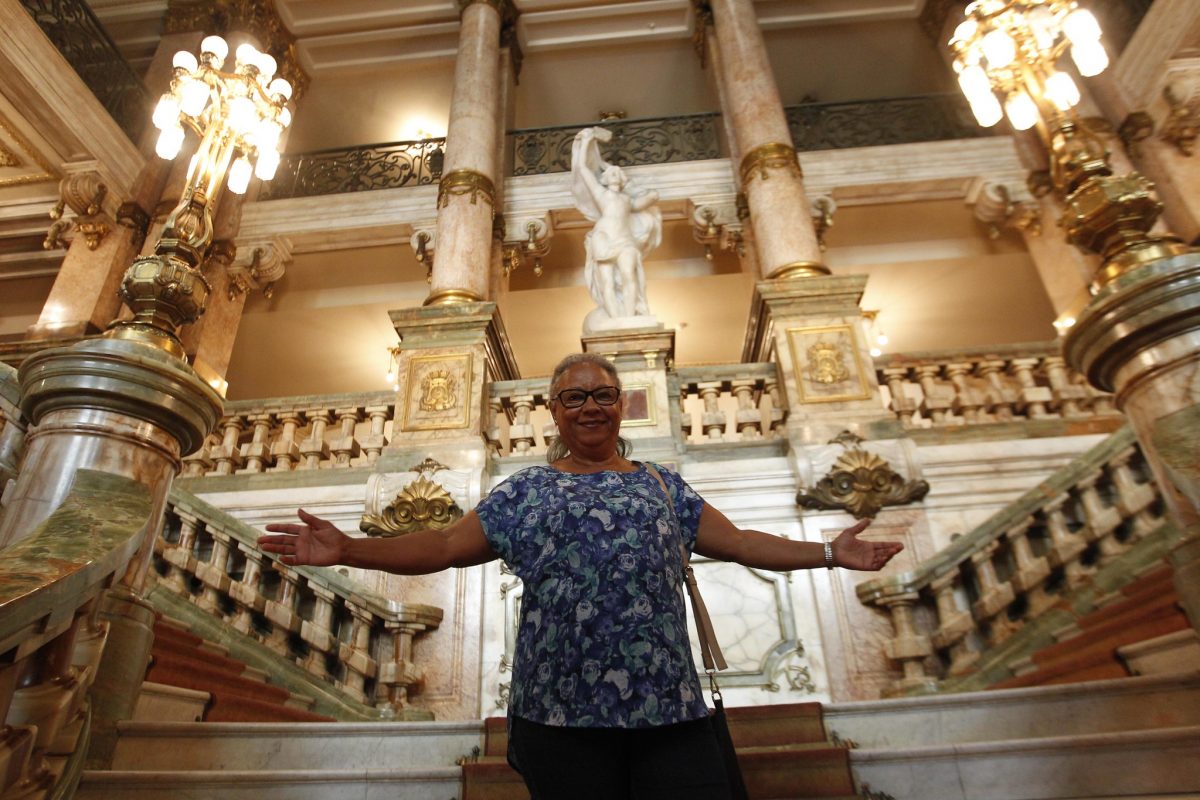 Kátia Motta, 68 anos, abre os braços na escadaria do Theatro Municipal: "Eu me sinto uma criança, descobrindo minha cidade". Foto: Paulo Sérgio / Prefeitura do Rio